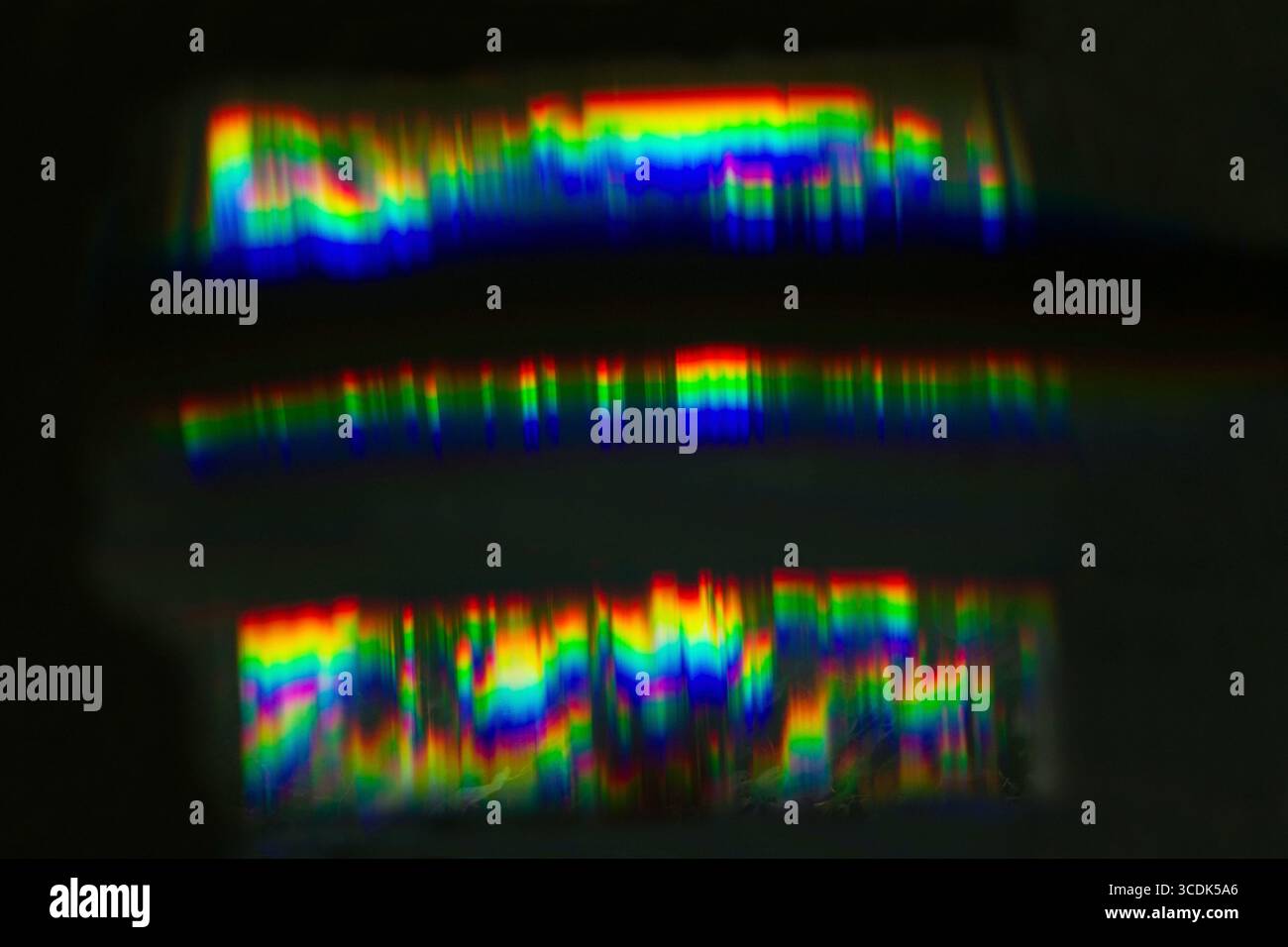 Motivi spettrali colorati creati dalla rifrazione della luce attraverso un prisma e motivi vibranti. Luce parassita dell'obiettivo iridescente. Foto Stock