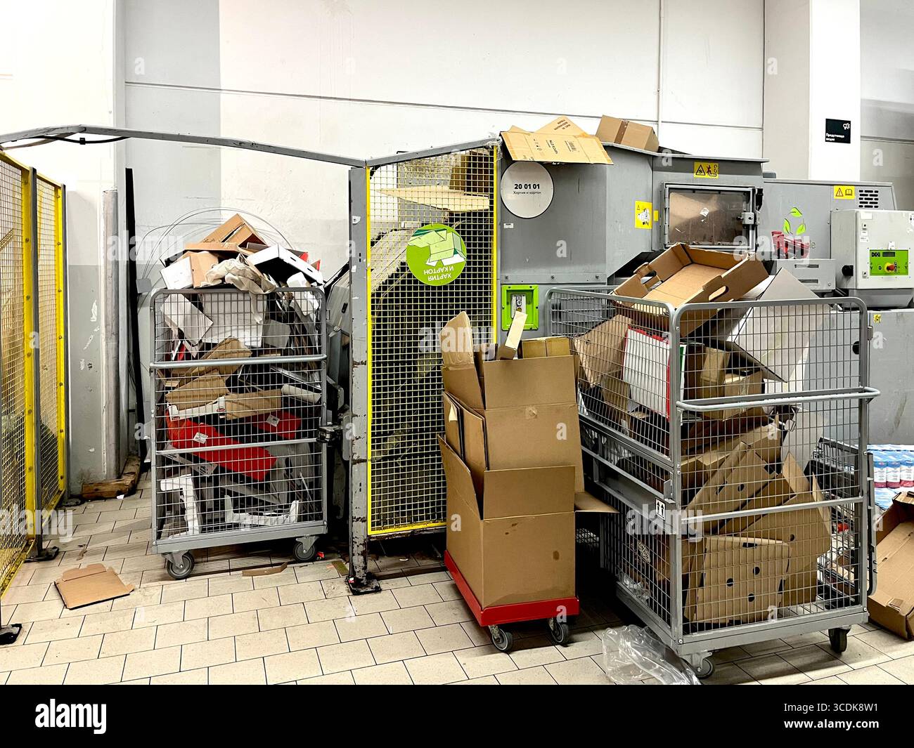 Pressa per balle in cartone e carrelli completi nel magazzino dei supermercati, processo di riciclaggio, gestione dei rifiuti al dettaglio e sostenibilità. Foto Stock