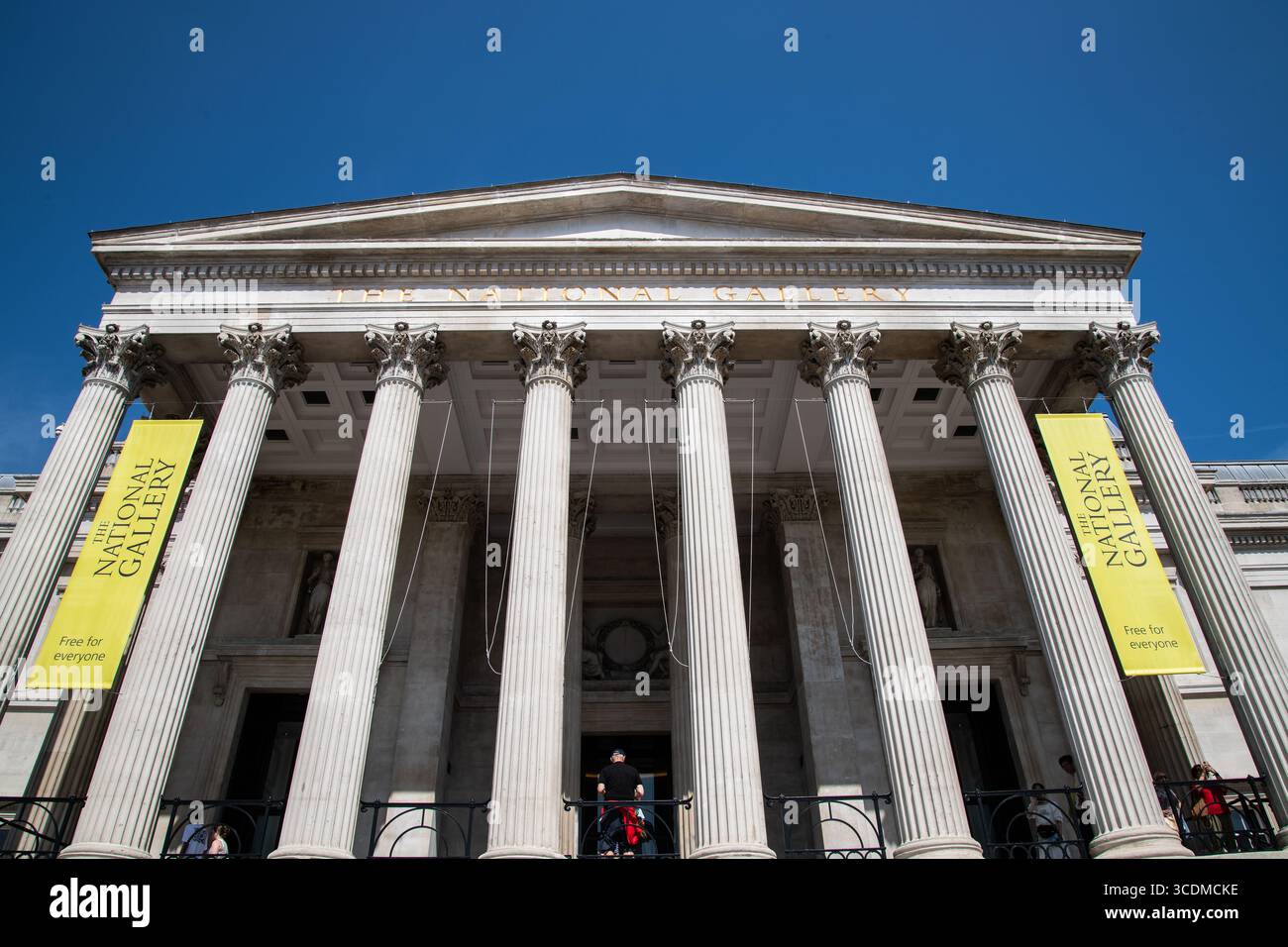 La facciata della National Gallery di Londra, sotto un cielo azzurro, mostra la sua architettura classica e la sua posizione iconica in Trafalgar Square. Foto Stock