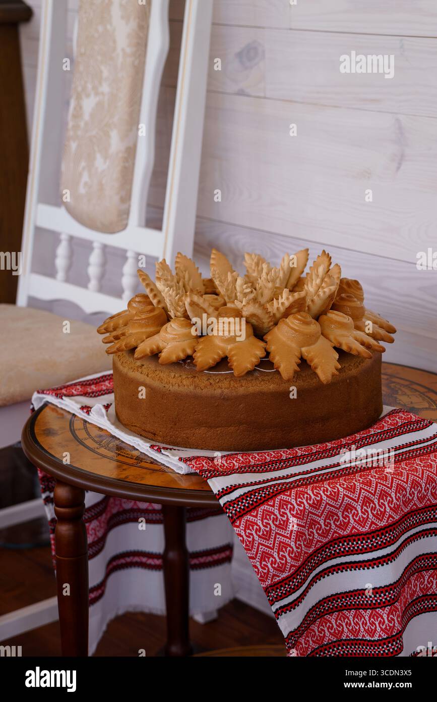 Una fotografia da vicino mostra una torta Ucraina a più strati riccamente adornata con un piccolo pesce pasticceria, allestita su un tavolo rotondo con un wh Foto Stock