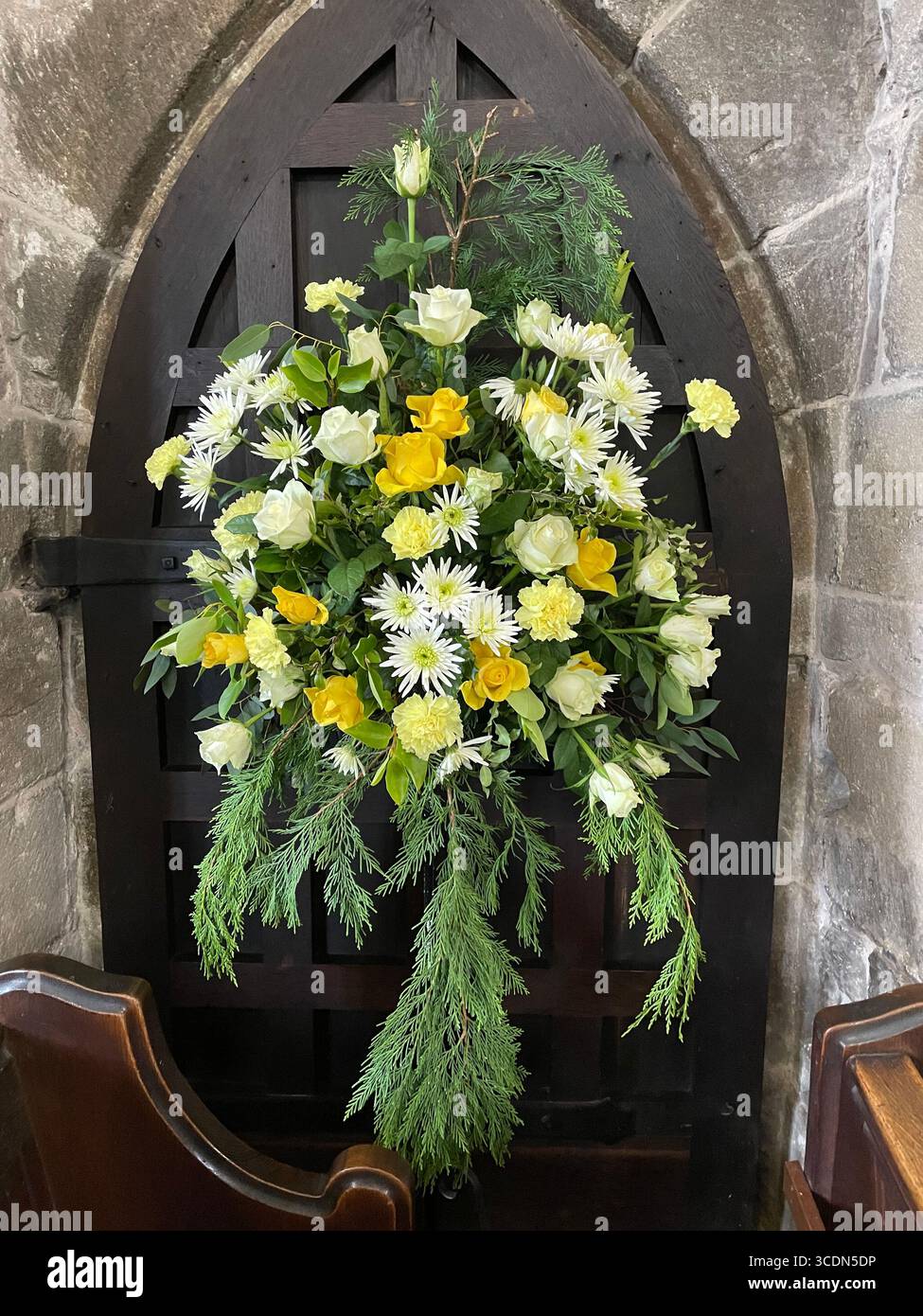 I fiori primaverili di colore giallo brillante e bianco adornano una tribuna della chiesa, accogliendo la stagione pasquale con vivaci fioriture stagionali. - Immagine stock catturata con smartphone