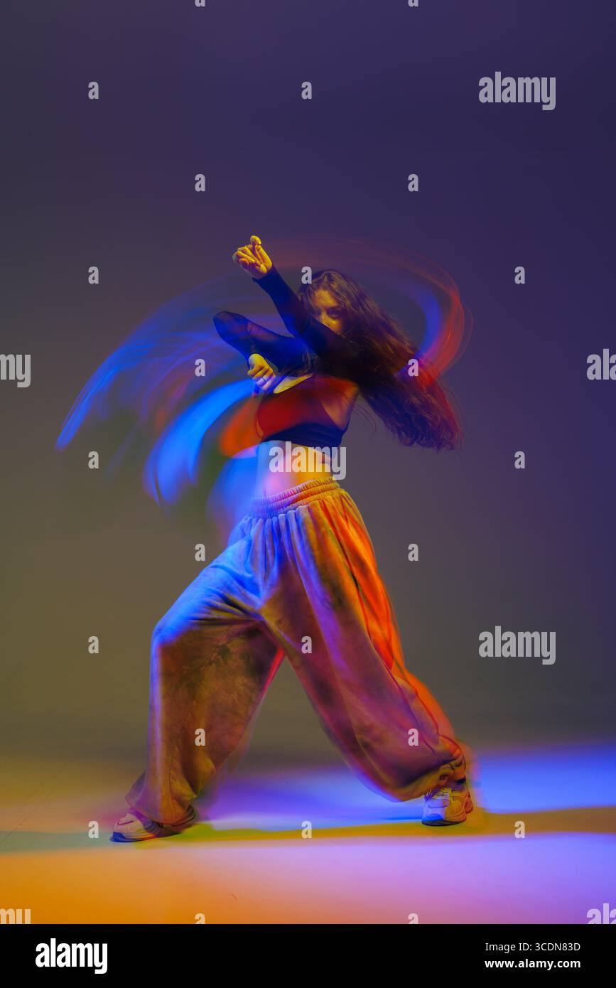 Ballerina jazz funk espressiva catturata in movimento energico con illuminazione vibrante, incarnando lo spirito della danza moderna. Foto Stock