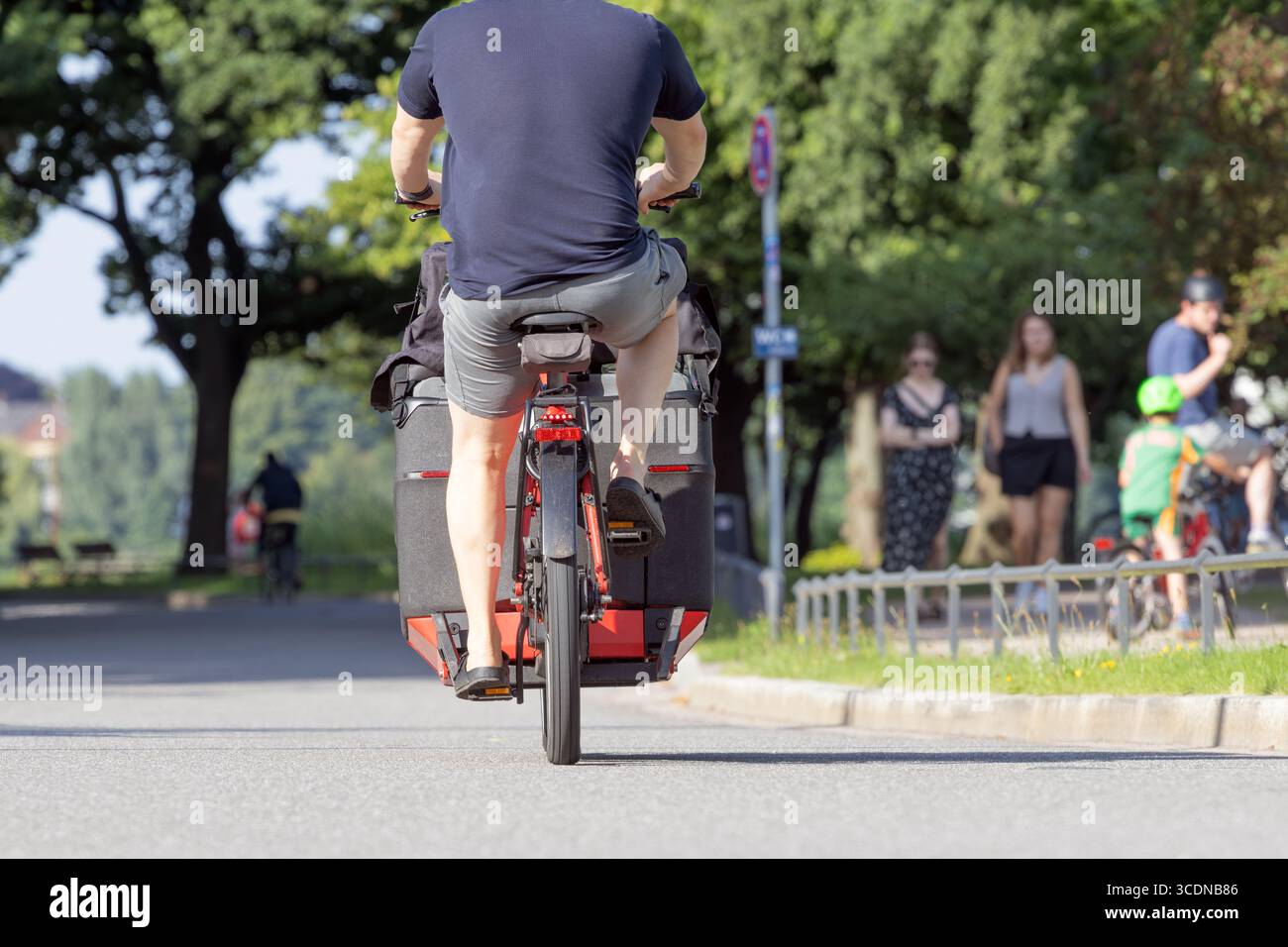 L'uomo in pantaloncini corre in bici cargo Foto Stock