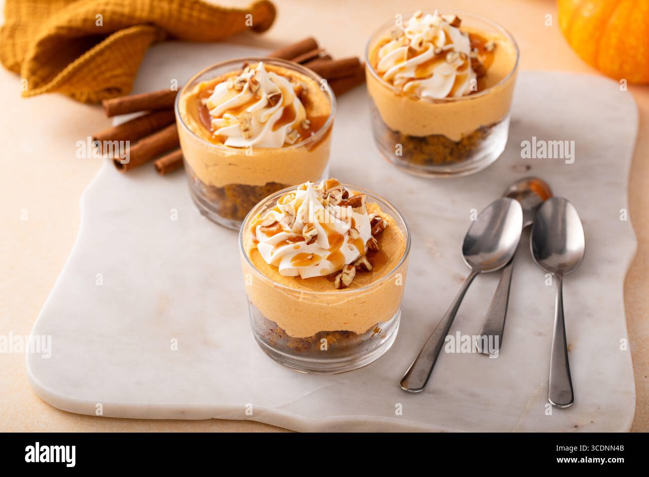 Cheesecake di zucca in un bicchiere con panna montata e noci pecan, idea di dessert autunnali, niente dolci al forno per il giorno del Ringraziamento Foto Stock
