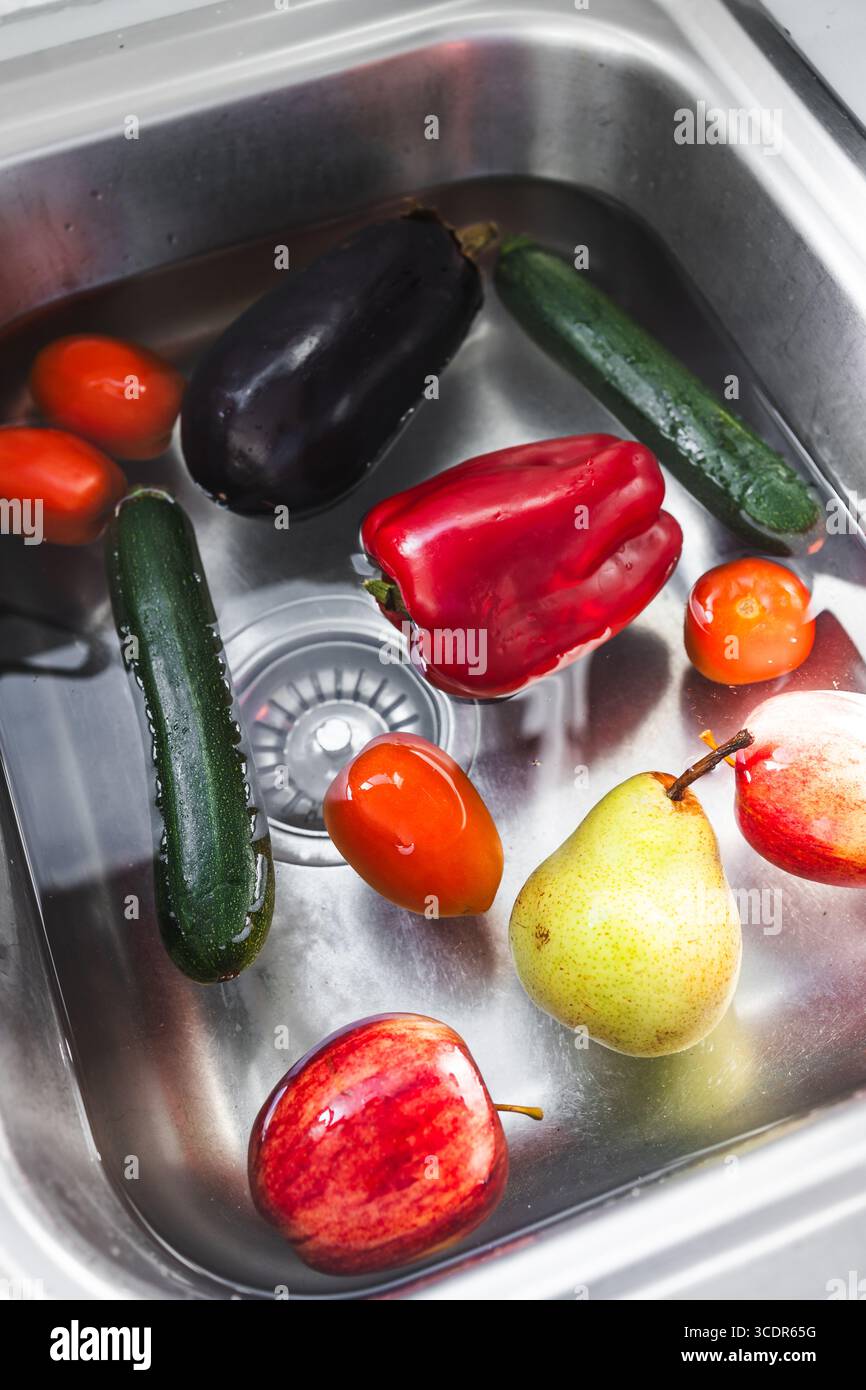 miscelare frutta e verdura immersi in bicarb soda nel lavandino per rimuovere i pesticidi Foto Stock miscelare frutta e verdura immersi in bicarb soda nel lavandino per rimuovere i pesticidi Foto Stock