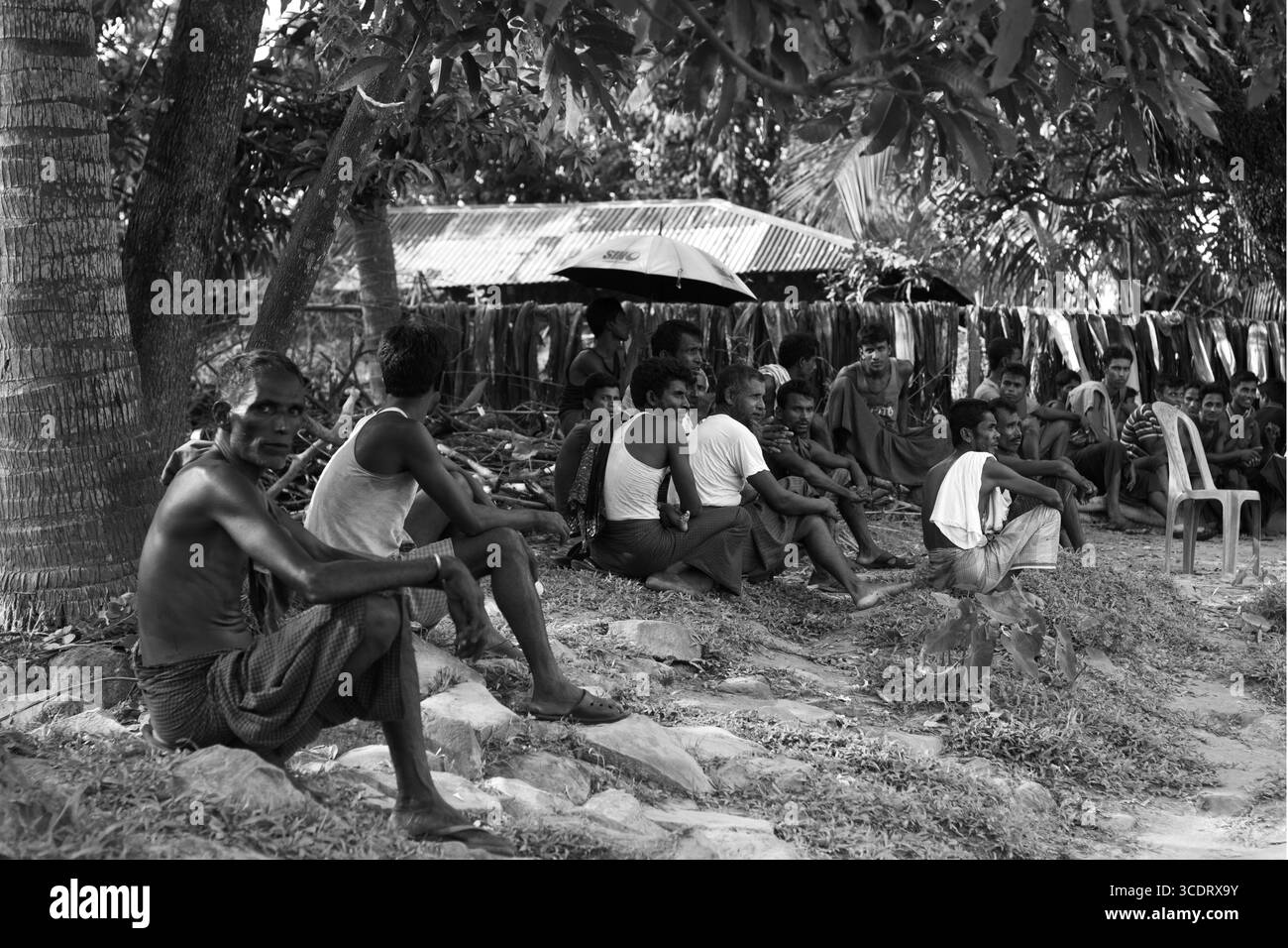 I rifugiati Rohingya si rifugiano vicino al confine di Tumru. Dietro di loro, un centro medico temporaneo fornisce assistenza sanitaria in Bangladesh. Foto Stock