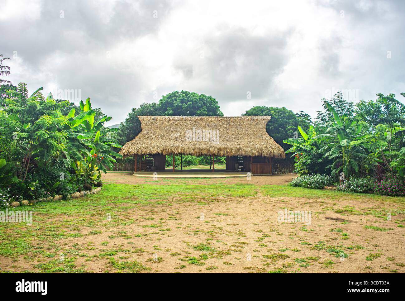 Un pittoresco edificio sul tetto di paglia circondato da lussureggiante vegetazione a Palomino, la Guajira, Colombia, in una giornata nuvolosa. Foto Stock