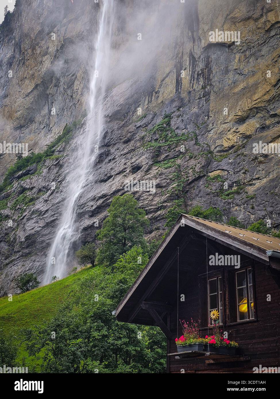 Casa alpina sotto la cascata Staubbach a Lauterbrunnen, Svizzera Foto Stock