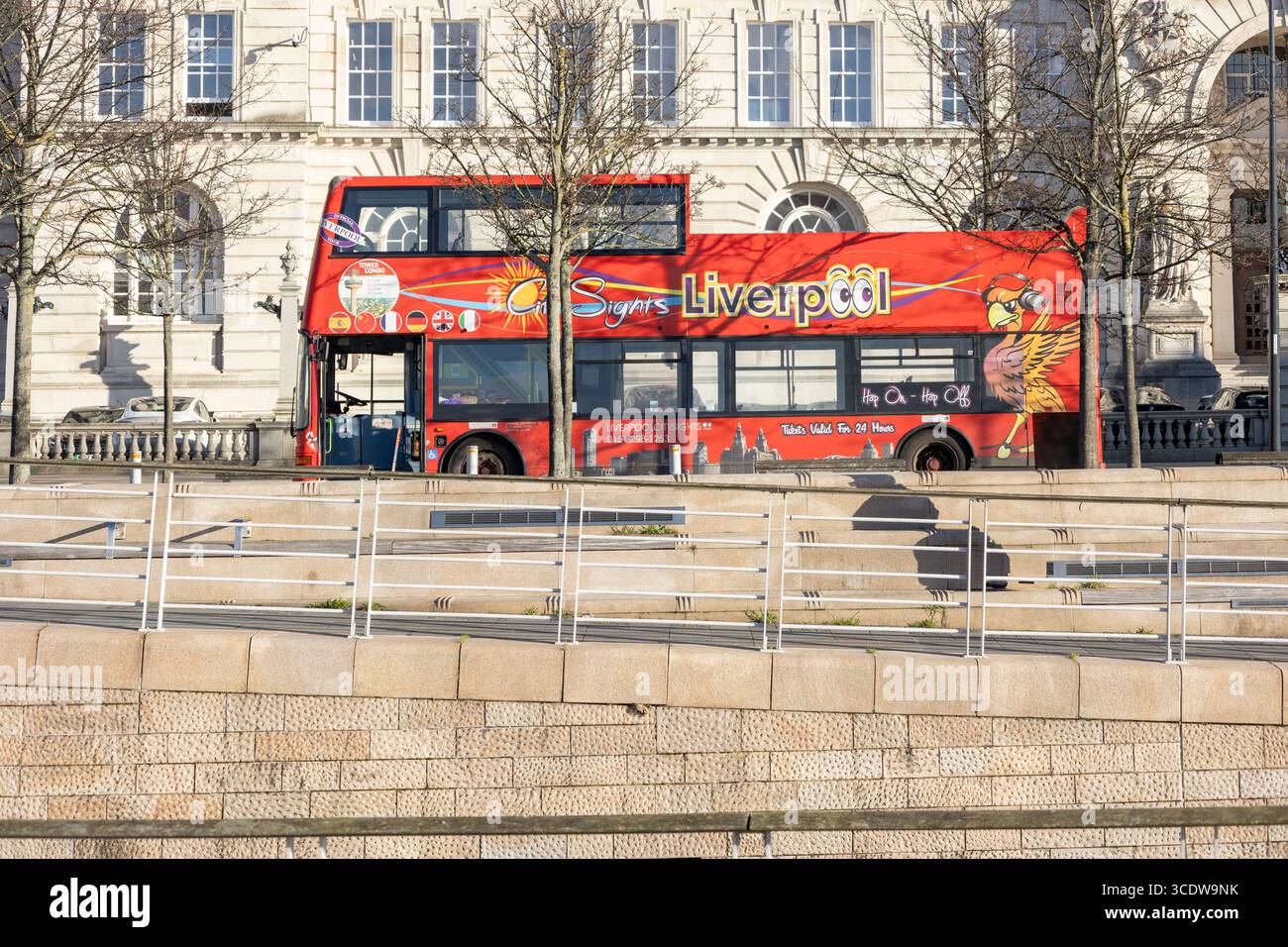 Liverpool, regno unito 16 gennaio 2024 Un autobus turistico a due piani rosso vivace, adornato di grafica, parcheggiato vicino a un edificio storico su una S. Foto Stock