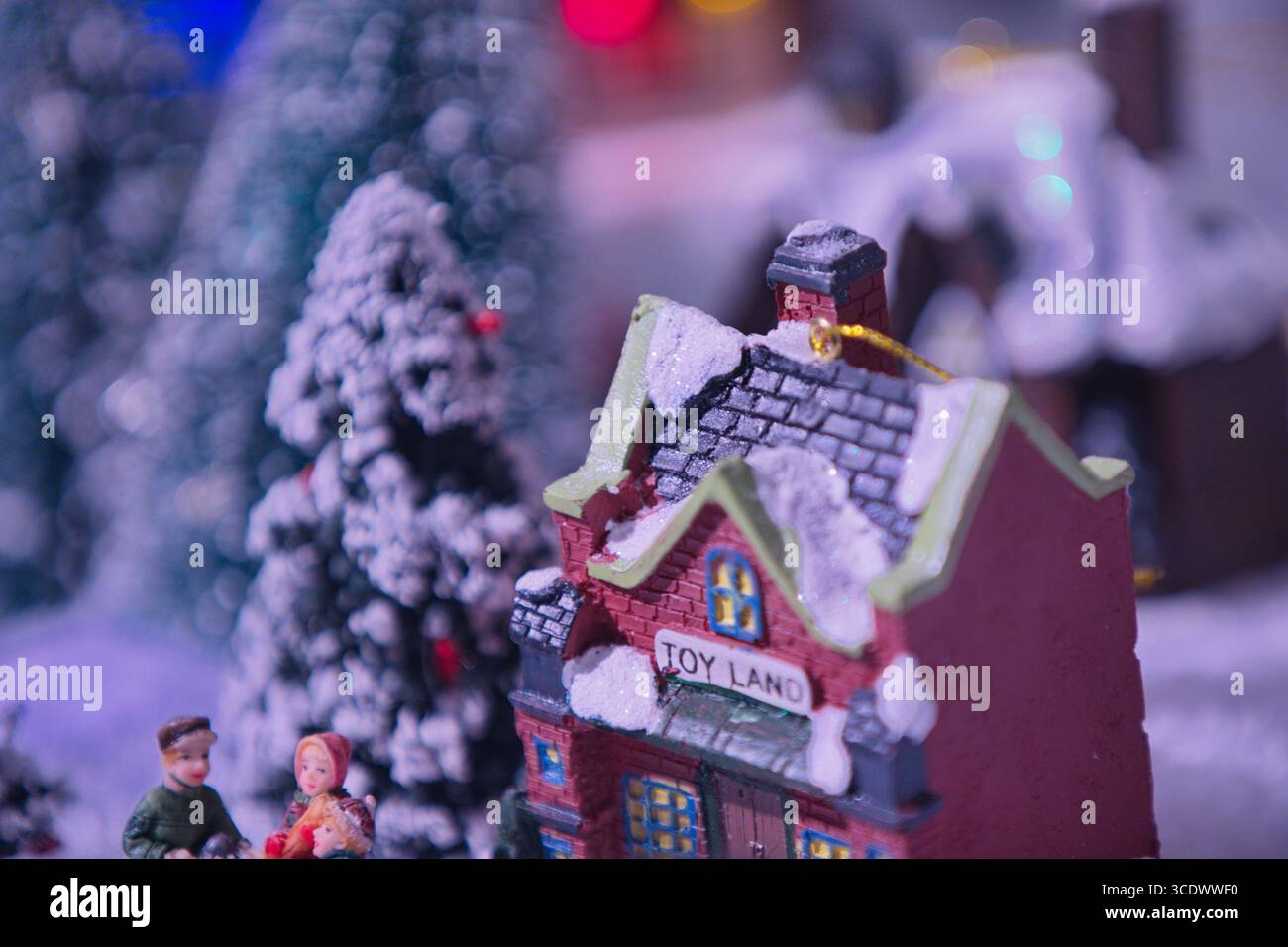 Villaggio invernale in miniatura con una casa dei giocattoli ricoperta di neve e piccole statuette tra alberi smerigliati e bokeh soffice, nella General Photography Collection. Foto Stock