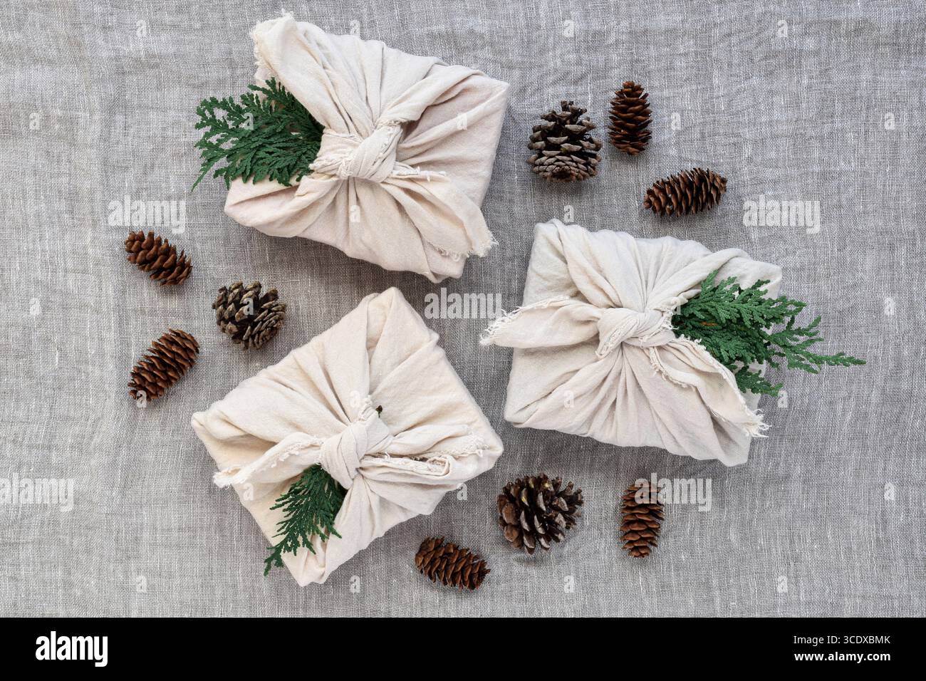 Gruppo di tre regali di natale avvolti in lino con pinne, confezione regalo ecocompatibile riutilizzabile, plantare con vista dall'alto Foto Stock