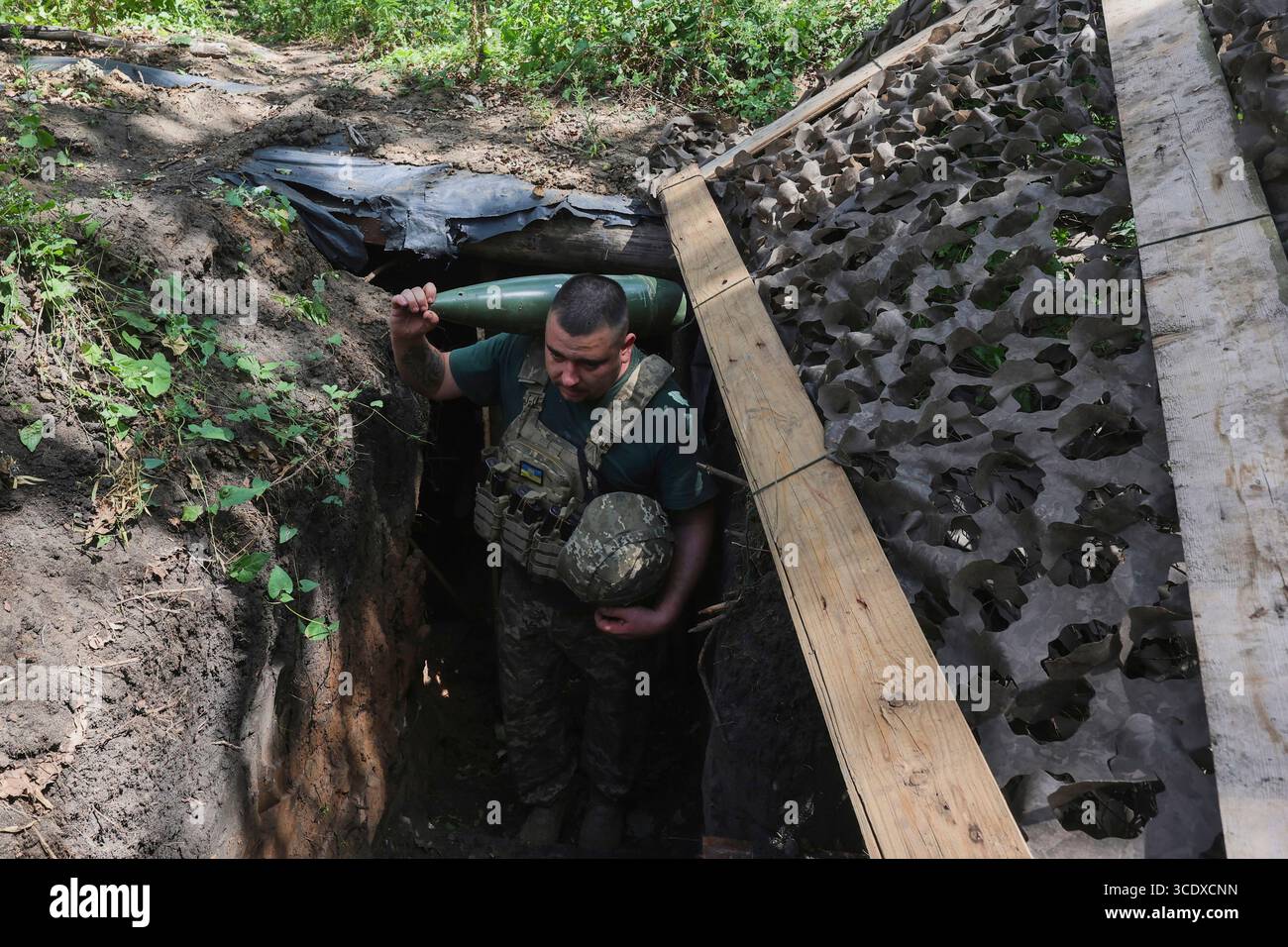 Un cannone di un'unità di artiglieria semovente 2S3 "Akatsiya" della 30a brigata meccanizzata separata intitolata al principe Kostiantyn Ostrozkyi porta un proiettile sulla spalla durante i preparativi per una missione di combattimento in direzione di Donetsk, Ucraina, il 13 agosto 2025 (foto di Viacheslav Madiievskyi/Ukrinform) Foto Stock