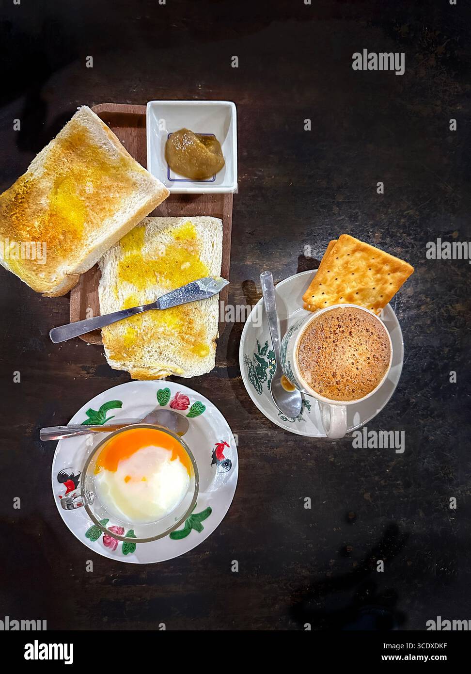 Colazione tradizionale malese, pane tostato, marmellata kaya, uova sode, caffè cracker su una superficie rustica in una caffetteria kopitiam di kuala lumpur, malesia Foto Stock