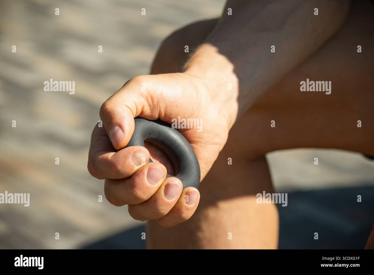 L'uomo rafforza la sua presa con un espansore in gomma nera. Si vede tenere un espansore con una presa salda, suggerendo un esercizio concentrato. Primo piano. Foto Stock