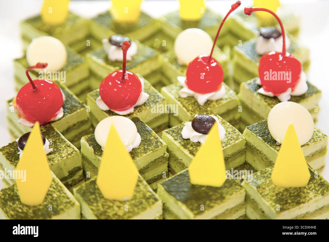 Torta con strato di tè verde con cioccolato, panna e ciliegia rossa. Foto Stock