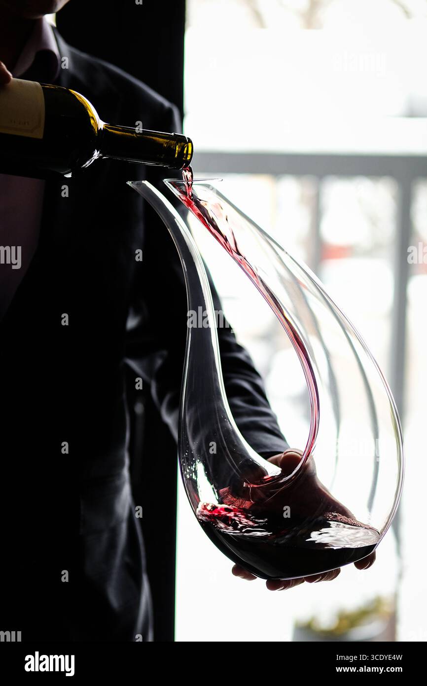 Un vino elegante che viene versato con grazia in un bellissimo Decanter per un piacere ancora maggiore Foto Stock