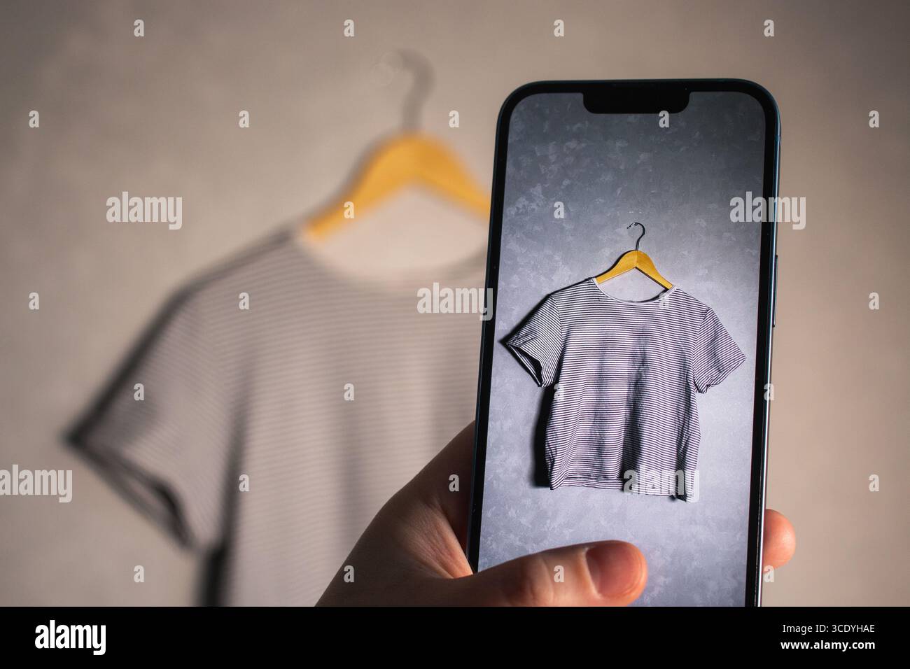 Donna che scatta una foto dei suoi vecchi vestiti per la rivendita. Concetto di seconda mano. Organizzazione dell'armadio. Foto Stock