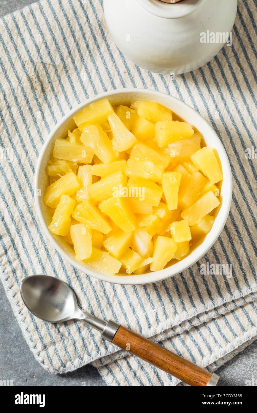 Il Tidbit di ananas in scatola biologico si divide in una ciotola da mangiare Foto Stock