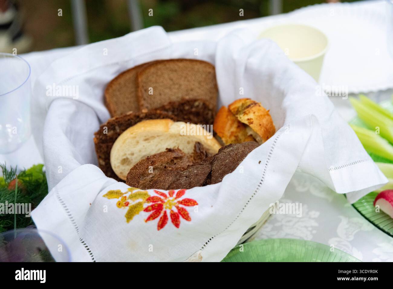 Una collezione di diversi tipi di pane esposta in un cestello in tessuto rivestito con un panno decorativo. la scena cattura una tavola rustica e invitante Foto Stock