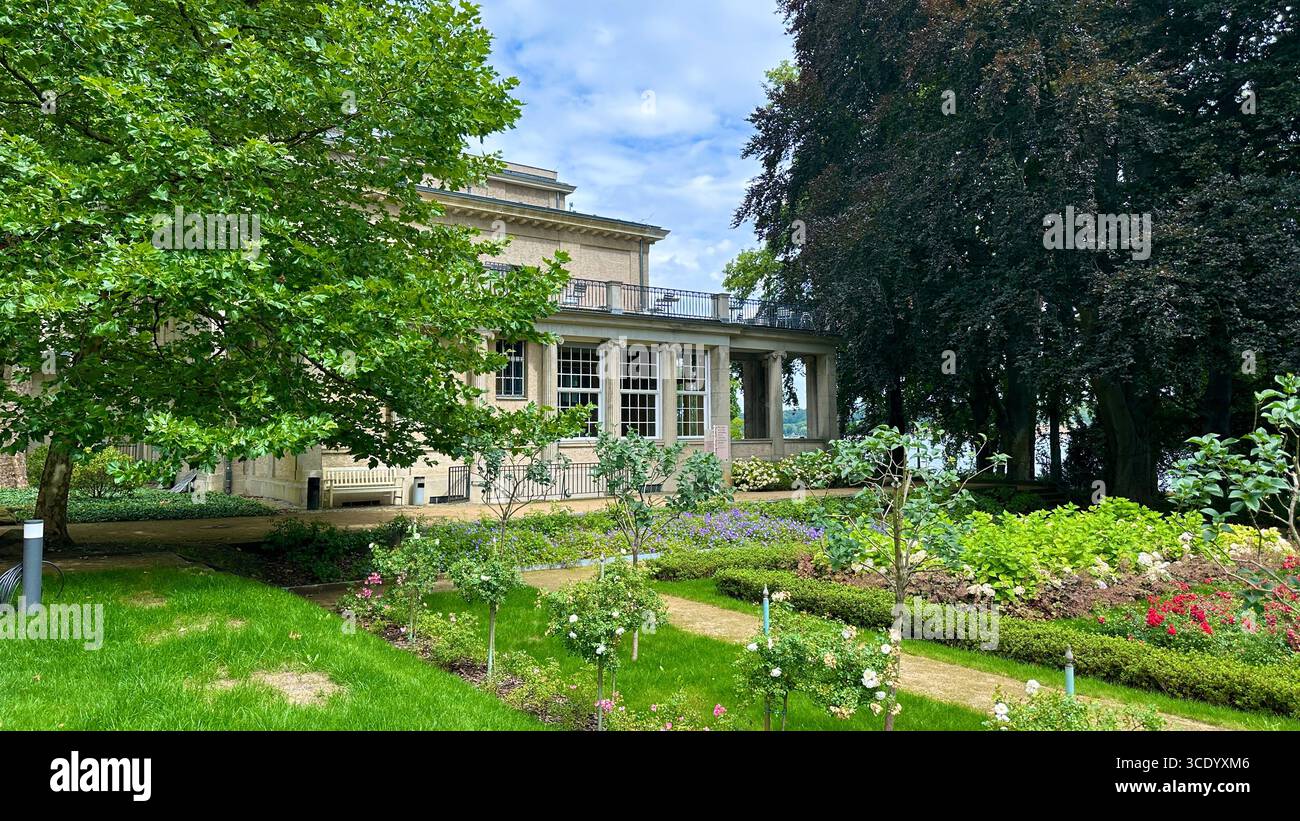 Vista laterale della conferenza House of the Wannsee a Berlino, Germania, con giardini curati in primo piano. Foto Stock
