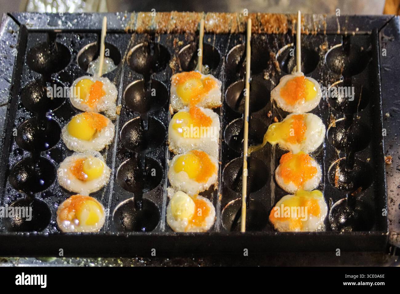 Cibo di strada uova di quaglia fritte in piccole formine, spiedate e servite in un mercato notturno tailandese, simboleggiando l'autentico turismo culinario del sud-est asiatico. Foto Stock