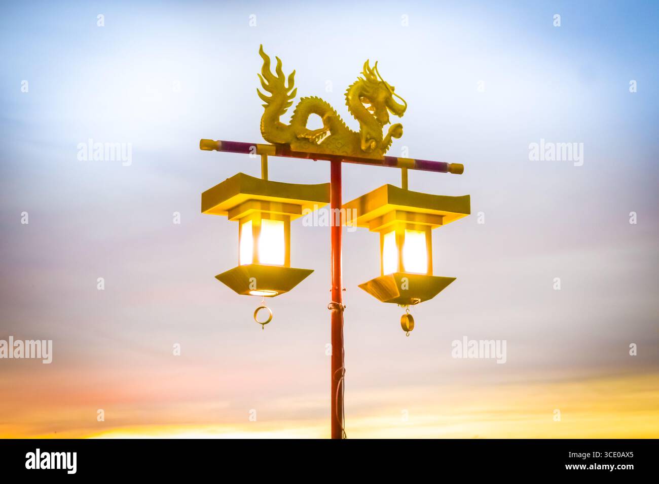Una lanterna di strada del drago d'oro che si illumina di un cielo colorato al tramonto, simbolo della cultura cinese e del festival del Capodanno cinese. Foto Stock