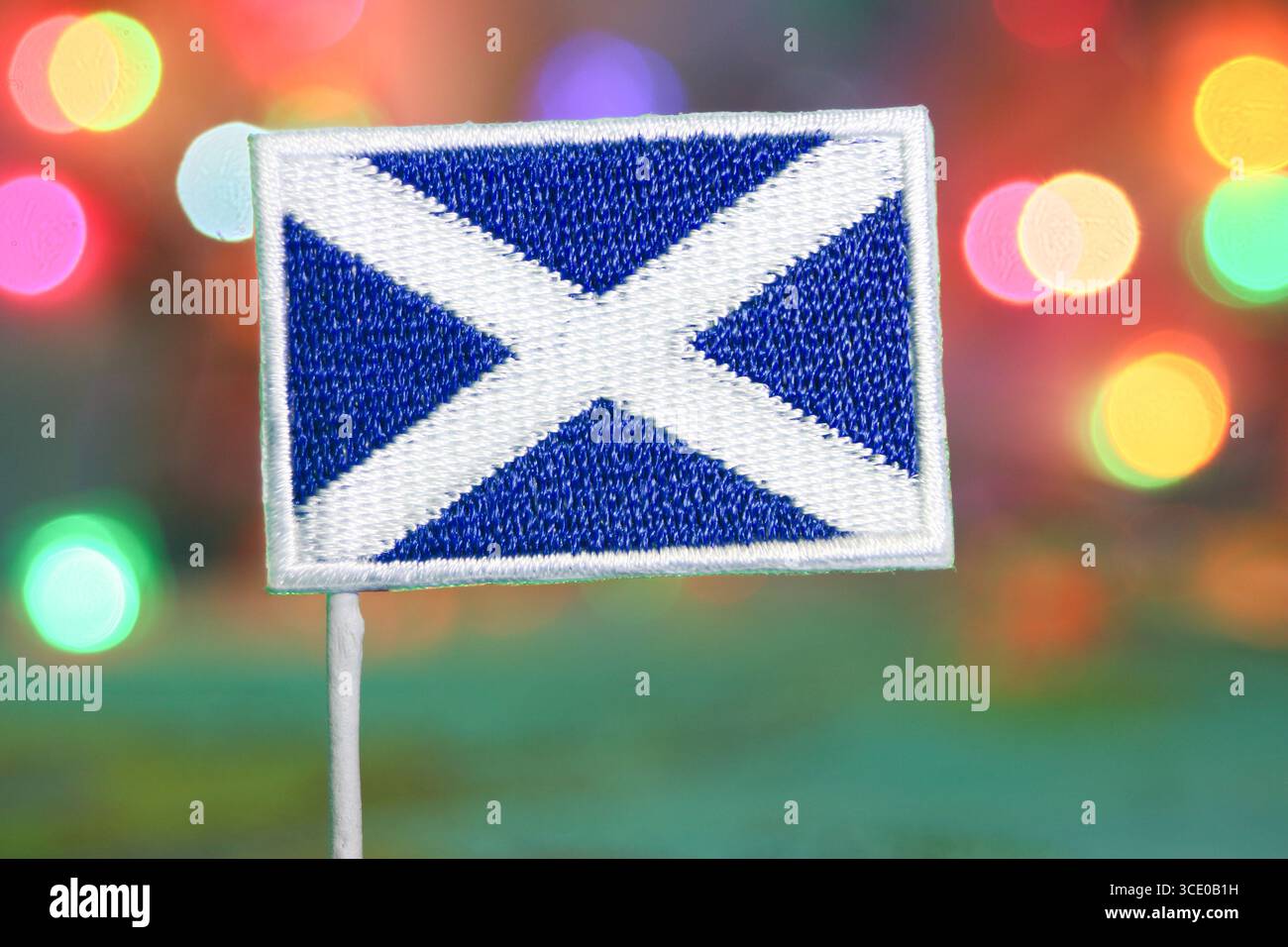 Bandiera scozzese ricamata con sfondo bokeh colorato, perfetta per feste come i fuochi d'artificio di Natale o Capodanno. Foto Stock