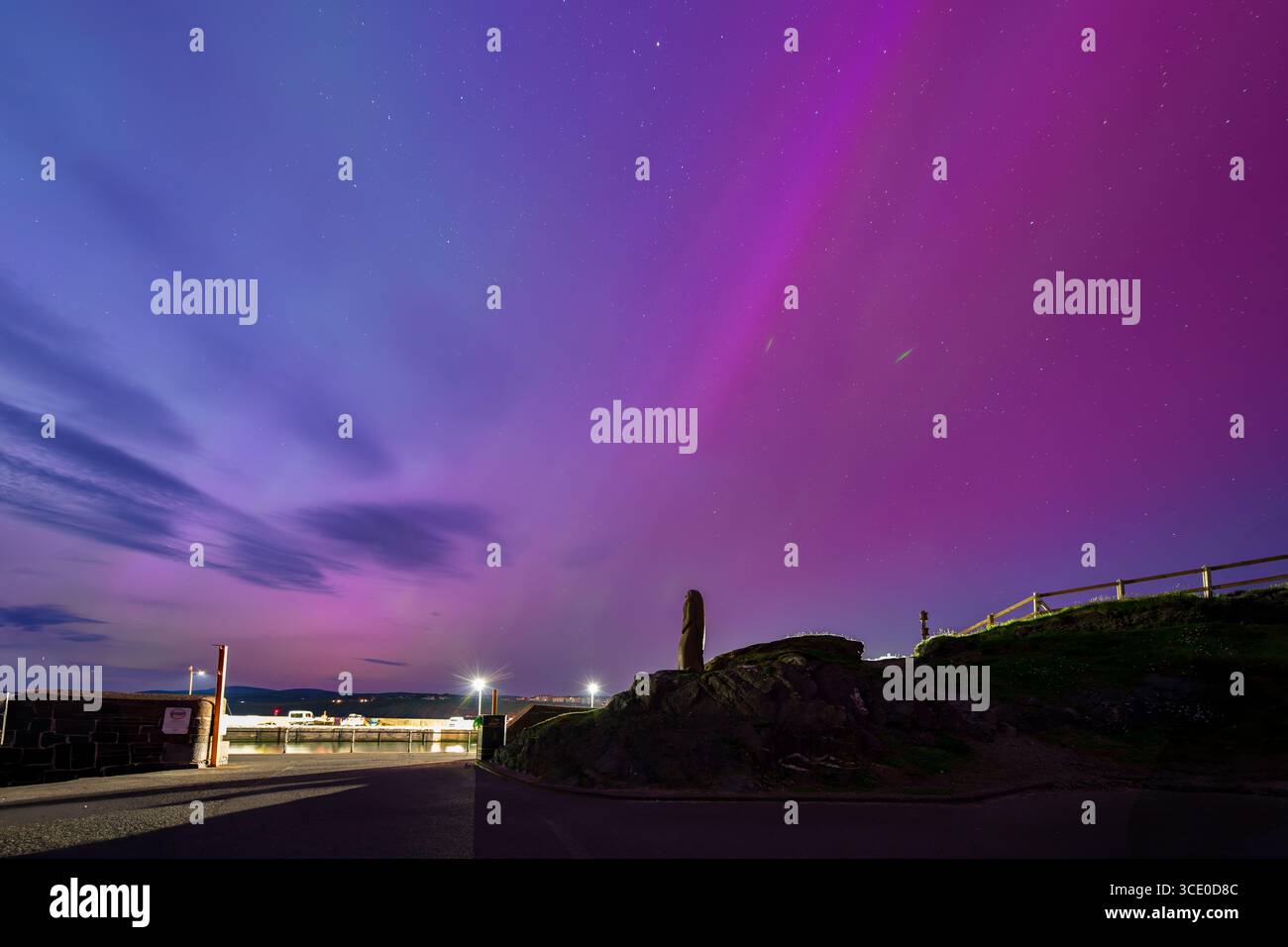 L'iconica spiaggia di Fenella con la statua della "Signora dell'Isola" sagomata su un cielo mozzafiato abbellito da vibranti colori viola e rosa. Foto Stock