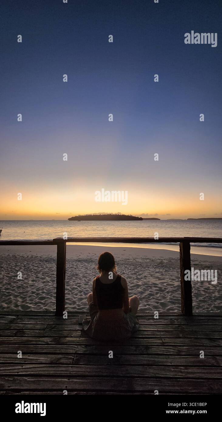 una persona seduta su un ponte guarda un tramonto tropicale sul vavau nella parte settentrionale di tonga Foto Stock