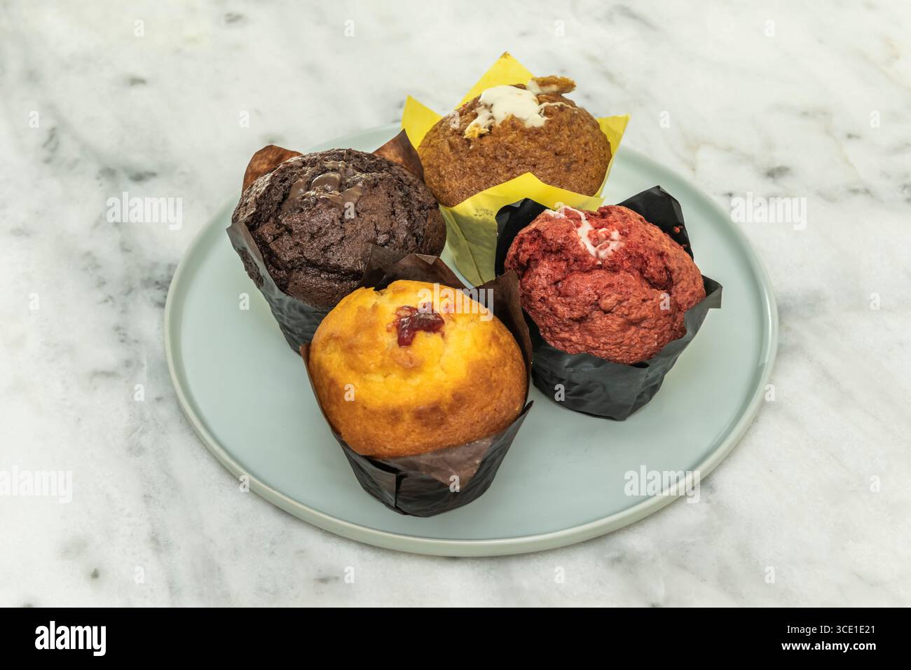 Deliziosi muffin classici soffici ricoperti da una liscia glassa alla vaniglia e scaglie di cioccolato Foto Stock