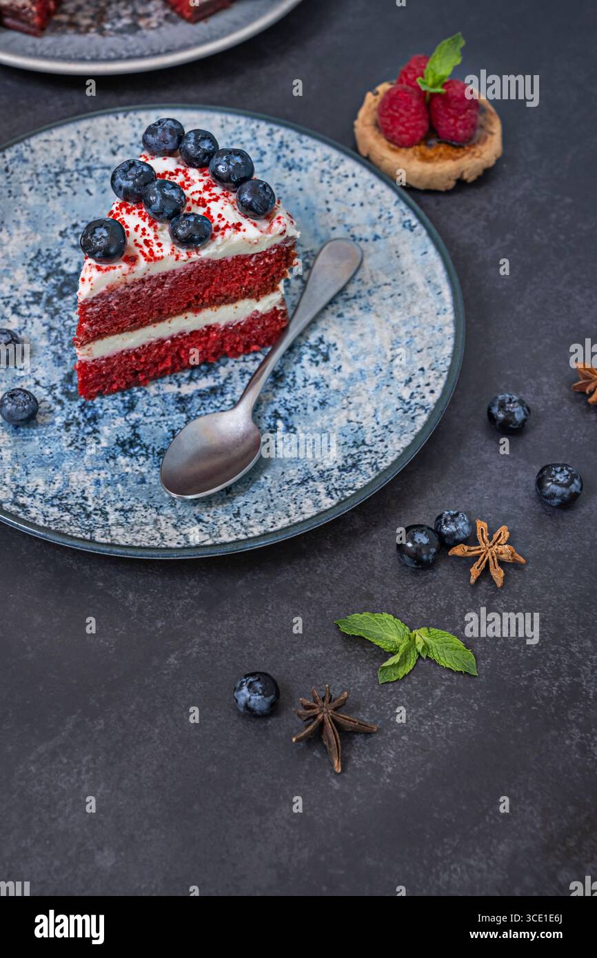 Velluto rosso con lampone in polvere: Condimento piccante con mirtilli freschi e scaglie di cioccolato Foto Stock