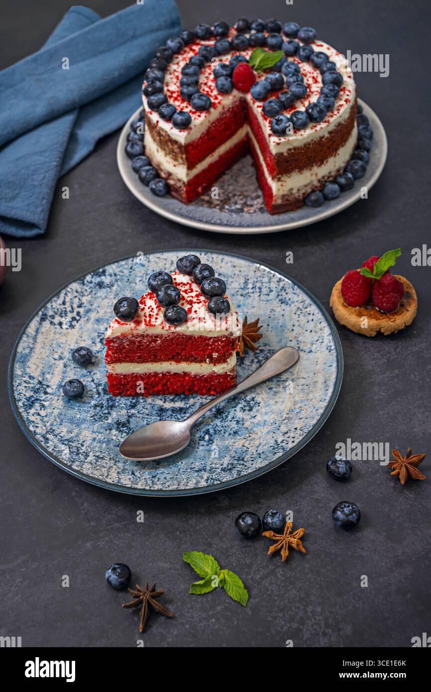 Drip Cake Red Velvet Cake: Glassa di cioccolato bianco che gocciola ai bordi con mirtilli congelati come gioielli ghiacciati Foto Stock