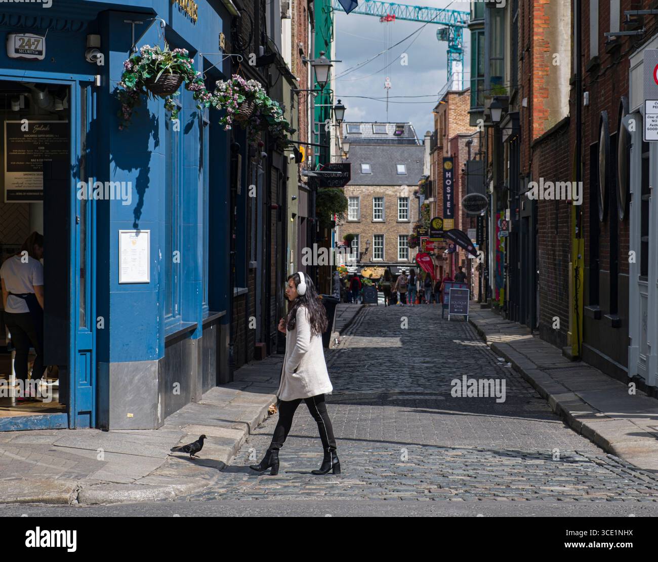 Donna che indossa le cuffie bianche Attraversare Tempio Lane South, Dublino, Leinster, Irlanda Foto Stock