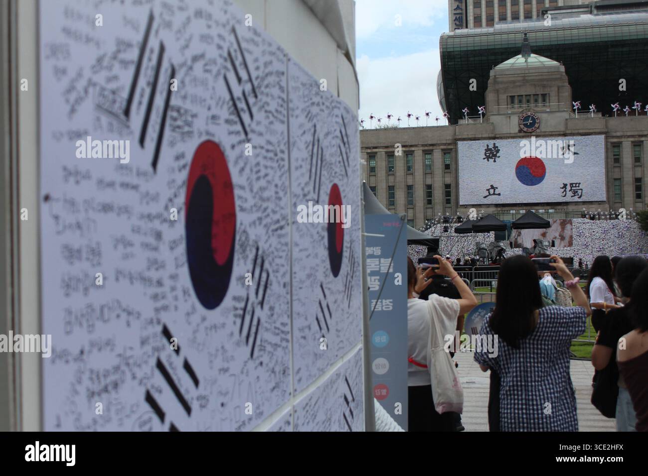 Seoul, Corea del Sud. 15 agosto 2025. I residenti di Seoul aspettano il concerto di fronte al municipio di Seoul, che è stato appositamente decorato per la giornata della Liberazione Nazionale della Corea. Crediti: Daniyar Atadjanov/Alamy Live News Foto Stock