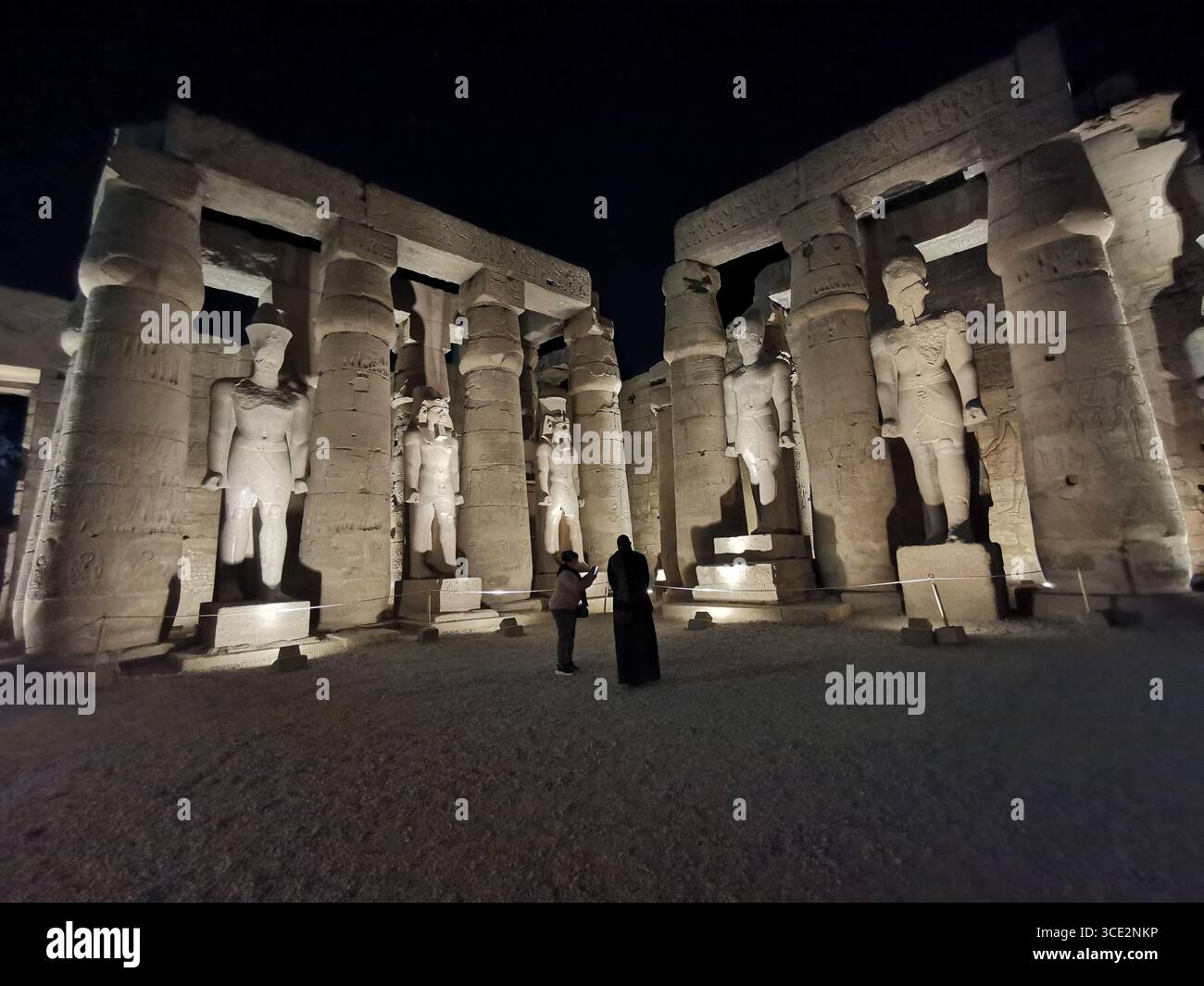 La sala peristilia del tempio di Luxor, costruita da Ramses II, illuminata di notte, fiancheggiata da colonne di loto e statue colossali del faraone. Foto Stock
