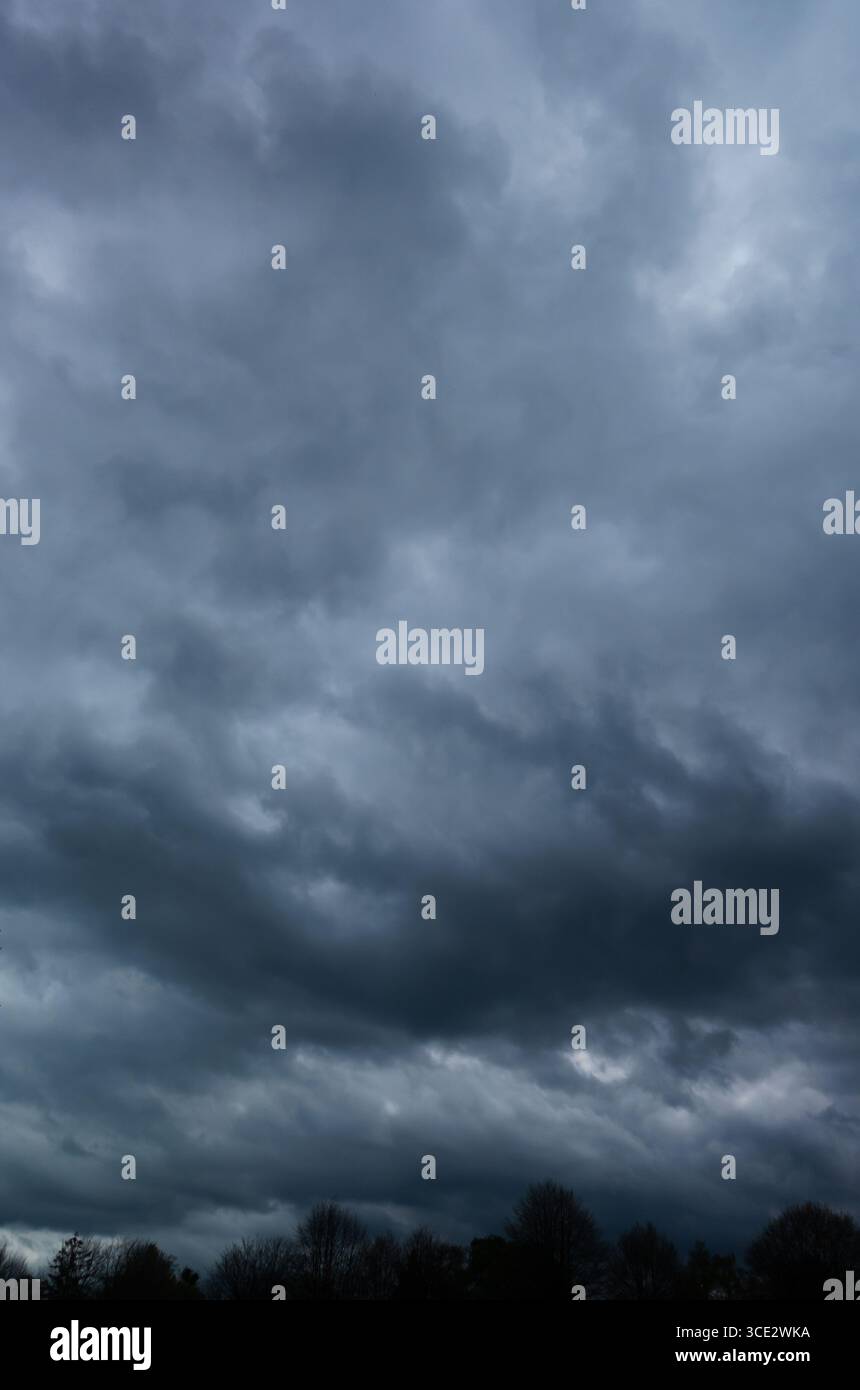 Spettacolari nuvole di tempesta che si radunano su un paesaggio buio e una scena meteorologica minacciosa Foto Stock