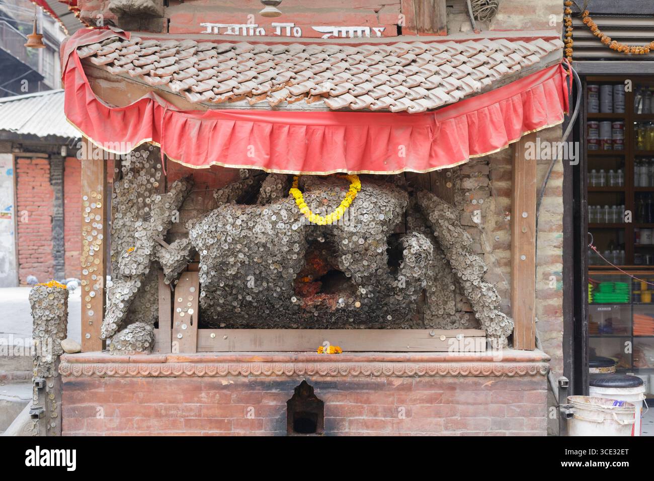 Offerte di monete al dio del mal di denti, Kathmandu, Nepal Foto Stock