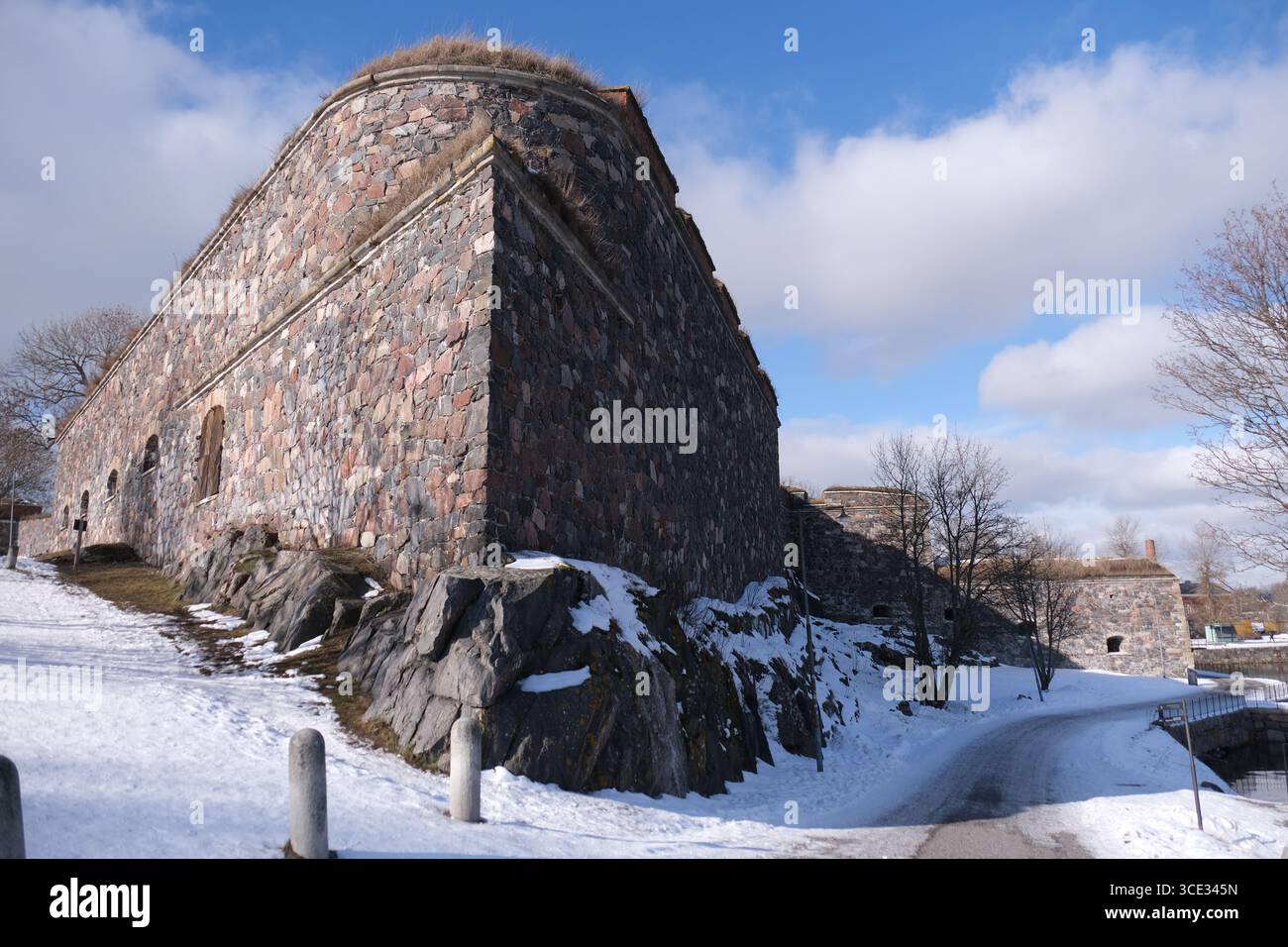 Edificio fortificato con mura di pietra ad angolo con sentiero pedonale coperto di neve. Foto Stock