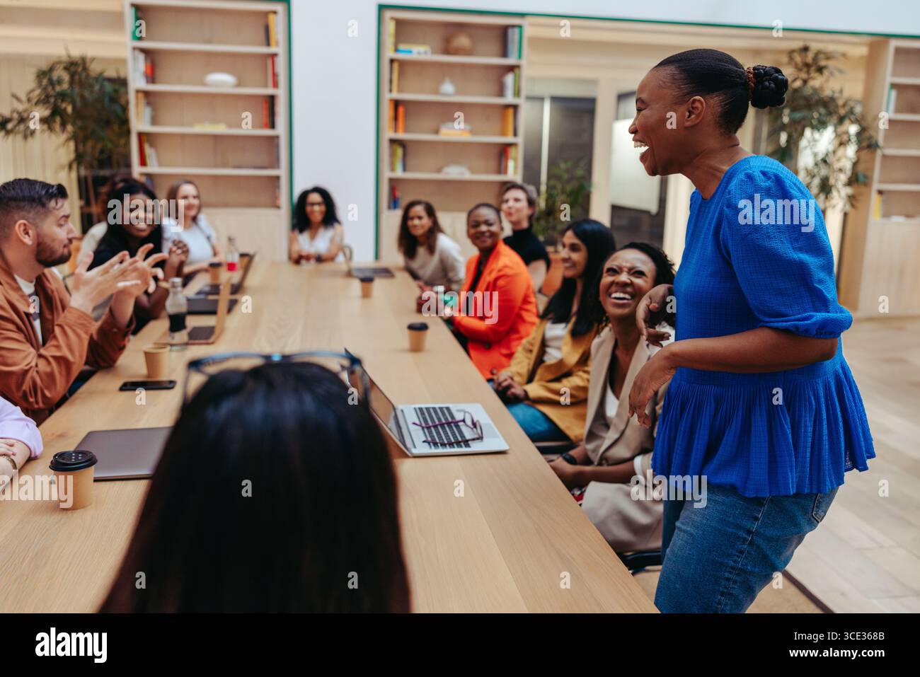 Un gruppo di professionisti diversi che partecipano attivamente a una riunione d'affari attorno a un grande tavolo. L'atmosfera e' vivace. Foto Stock