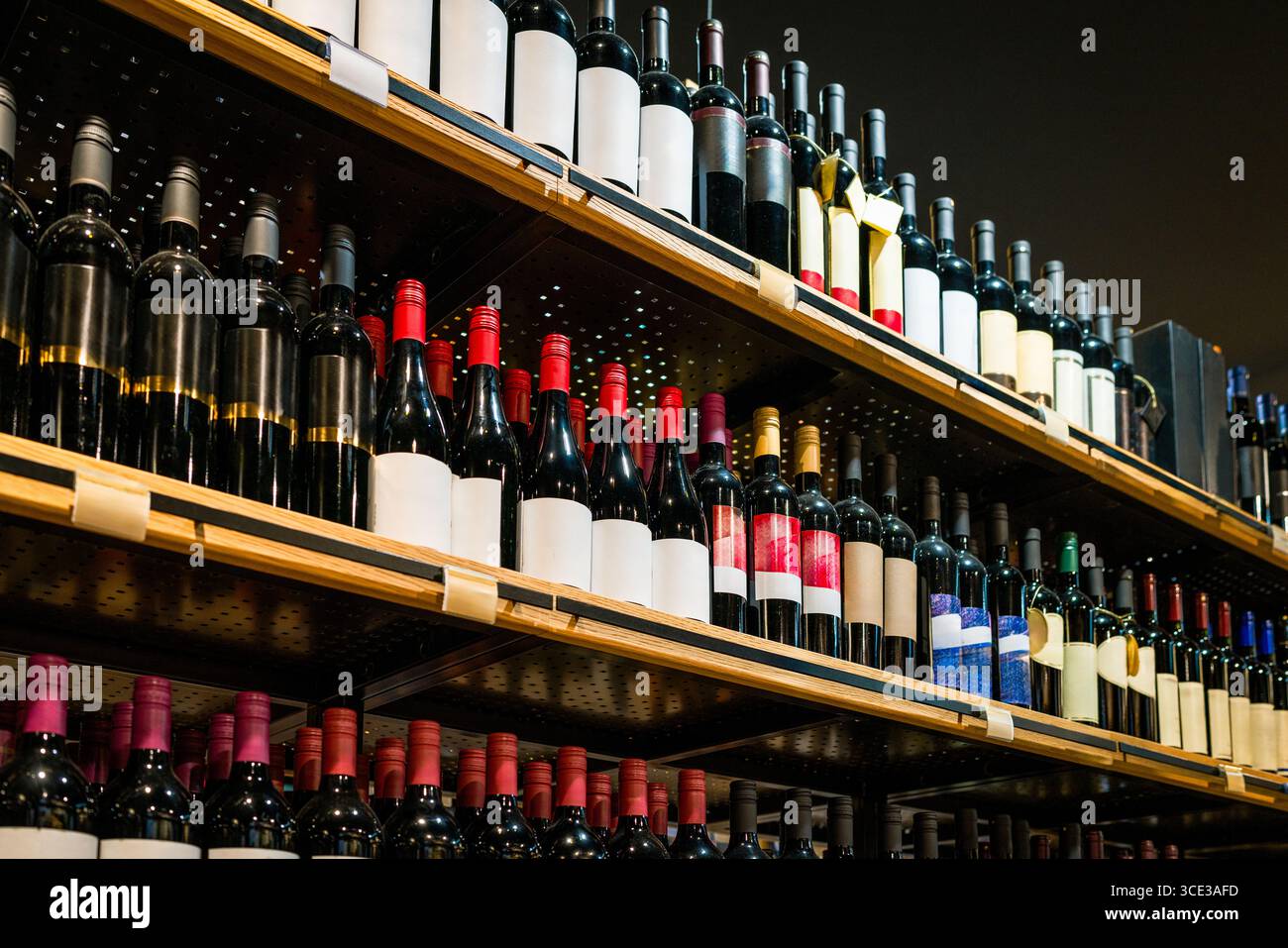 Vista ad angolo basso delle bottiglie di vino sugli scaffali del negozio di liquori Foto Stock