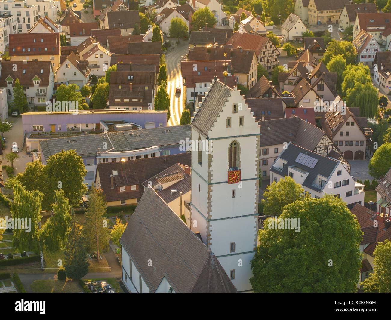 Case e chiesa in un villaggio con luce solare calda, paesaggi sul tetto e alberi verdi visibili, Aidlingen distretto di Boeblingen, Germania Foto Stock