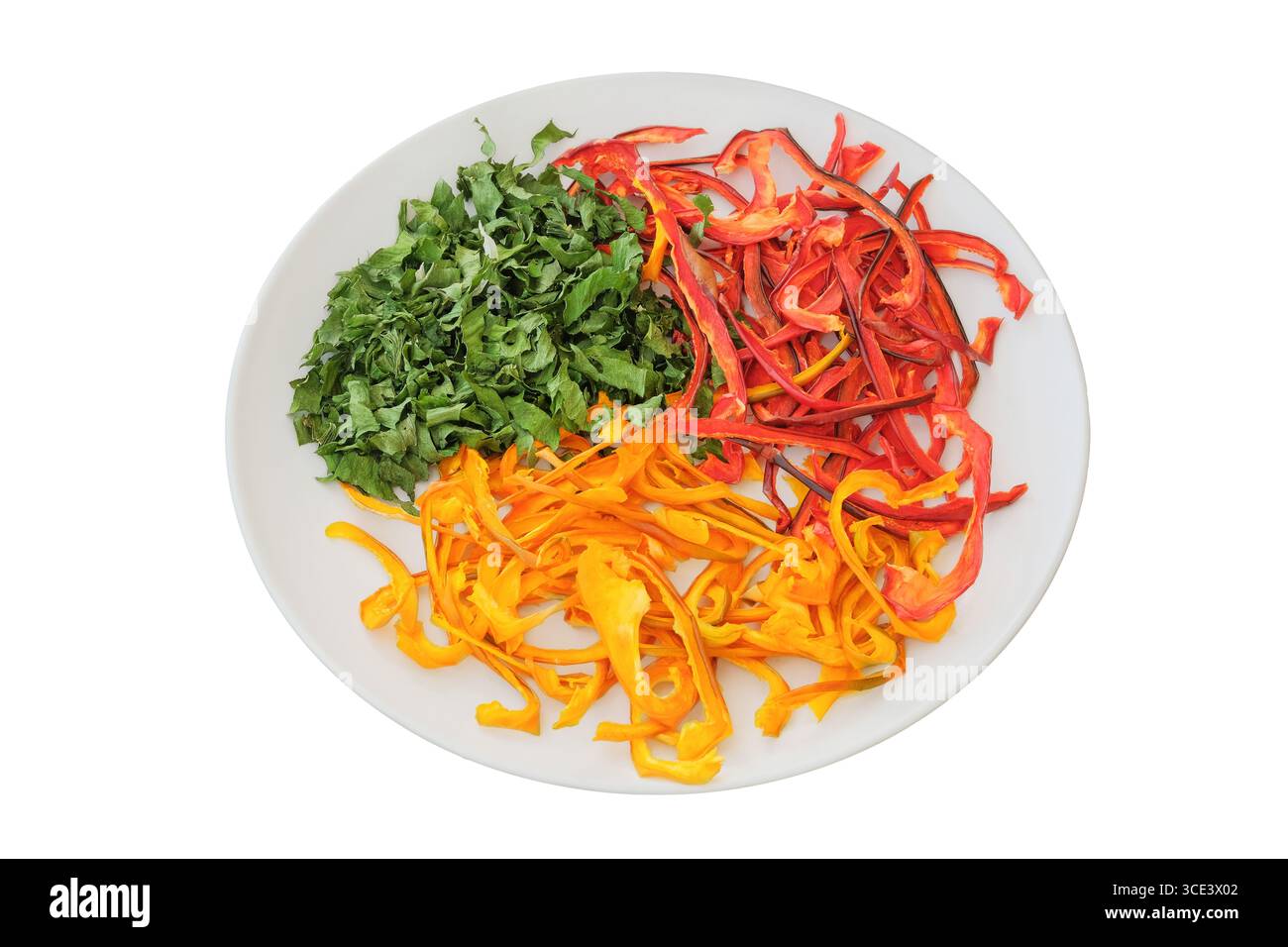 Peperoni dolci secchi e prezzemolo su un piatto di ceramica isolato su sfondo bianco. Varie verdure secche. Ingrediente per preparare un liofilizzato Foto Stock