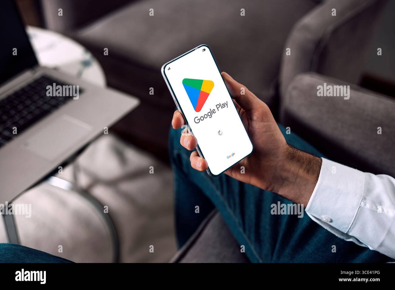 Google Play sullo schermo del telefono cellulare. Uomo che possiede uno smartphone che mostra la schermata di avvio dell'applicazione Play Store. Foto Stock