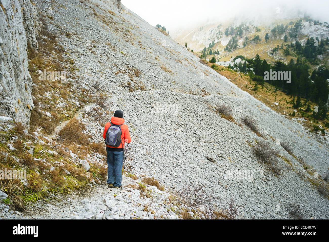 Un turista si trova su un sentiero stretto di fronte a un pendio di ghiaia a Komovi, in Montenegro. Turismo avventuroso e percorso escursionistico impegnativo Foto Stock