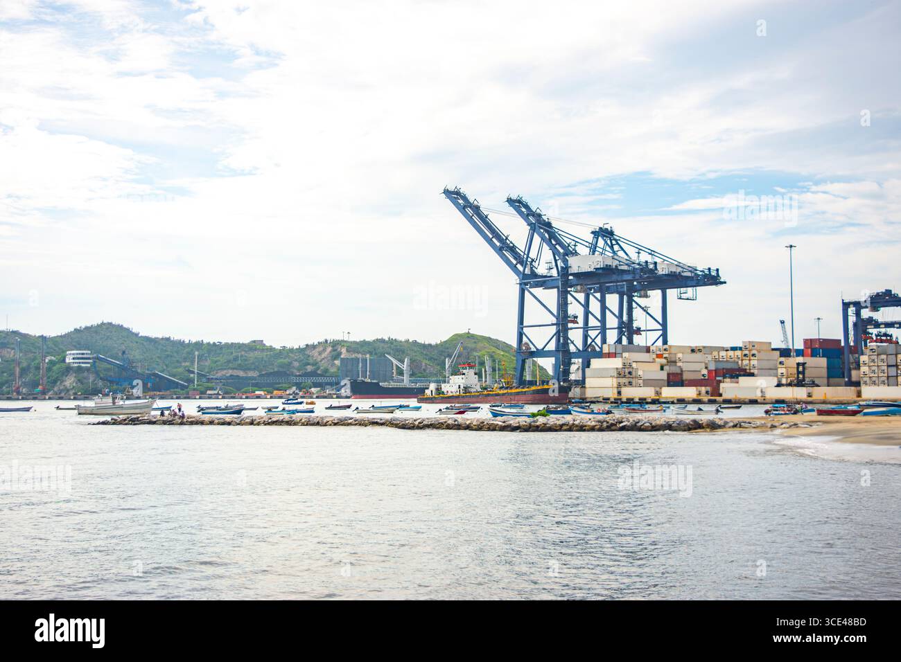 Vista di un porto industriale con gru, container e barche a Santa Marta, che mostra la logistica marittima e le attività sul lungomare. Foto Stock