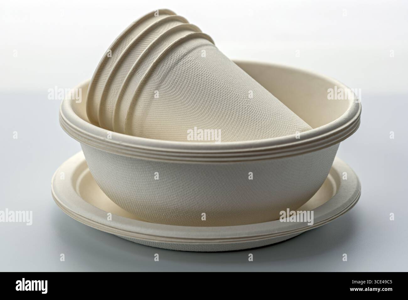 Ciotole e piatti di carta monouso ecocompatibili impilati su sfondo neutro, che offrono opzioni di stoviglie sostenibili per un ambiente attento all'ambiente Foto Stock