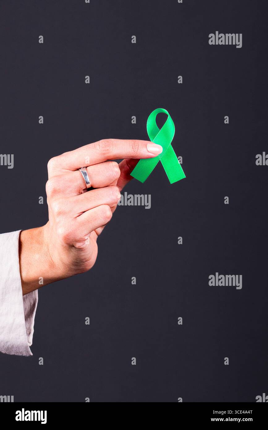 Mano della donna con un nastro verde, simbolo di consapevolezza della salute mentale, depressione e donazione di organi. Foto Stock