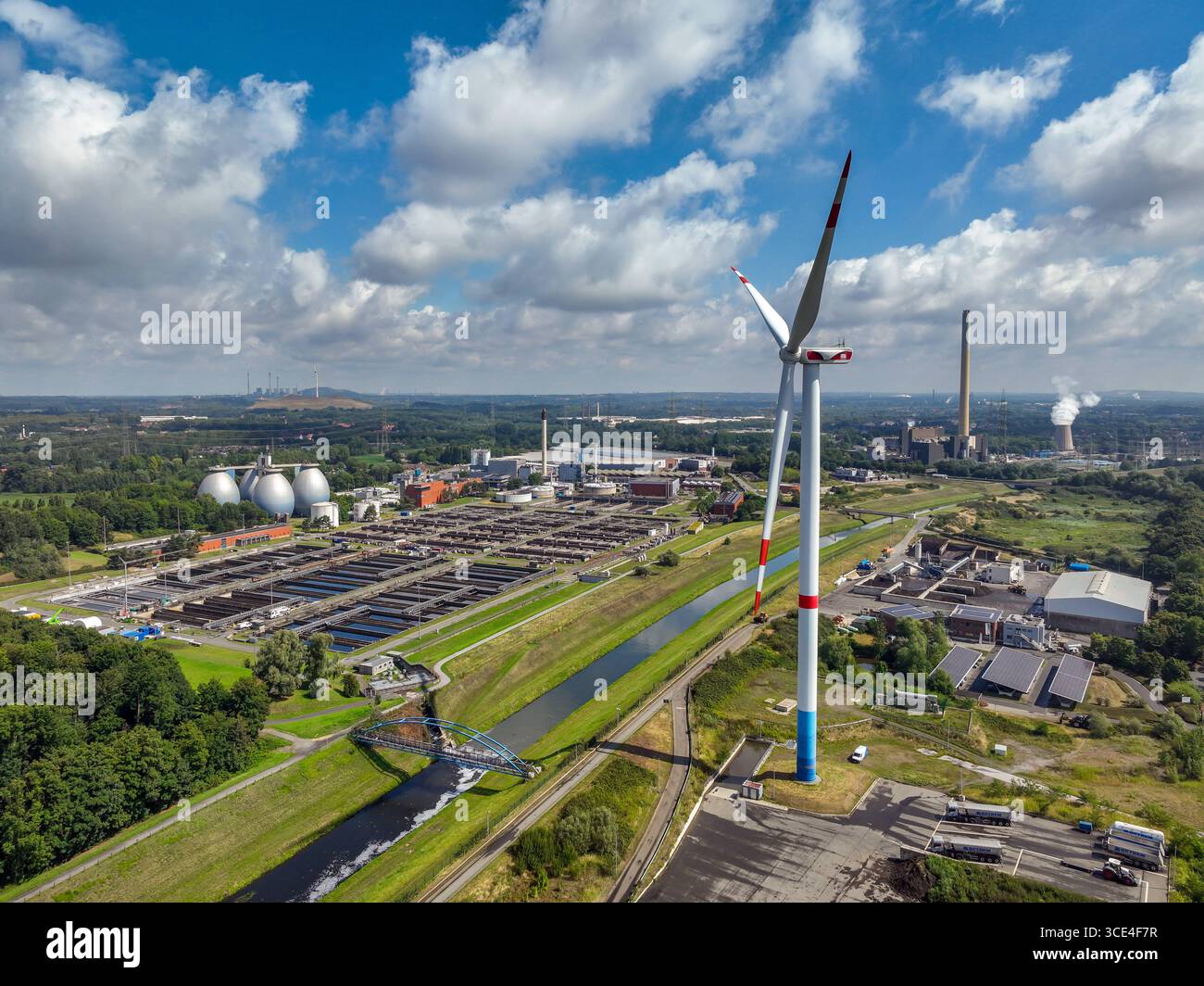 Bottrop, Nordrhein-Westfalen, Deutschland - Industrielandschaft im Ruhrgebiet, vorne das Windrad BETREM Emscherbrennstoffe GmbH und die Emschergenossenschaft Kläranlage Bottrop am Fluss Emscher, hinten Müllheizkraftwerk Essen-Karnap RWE Generation se. DAS Emscherklärwerk in Bottrop stellt eines der beeindruckendsten Bauwerke an der Emscher dar. Die vier Faultürme sind mit einer Höhe von 54 Metern und einem Gesamtvolumen von 54,000 Kubikmetern die Größten ihrer Art Die Klärbecken haben eine Gesamtfläche von 58,000 Quadratmetern und reinigen 8,500 Liter Wasser pro Sekunde. Auf einer Gesamtfläch Foto Stock
