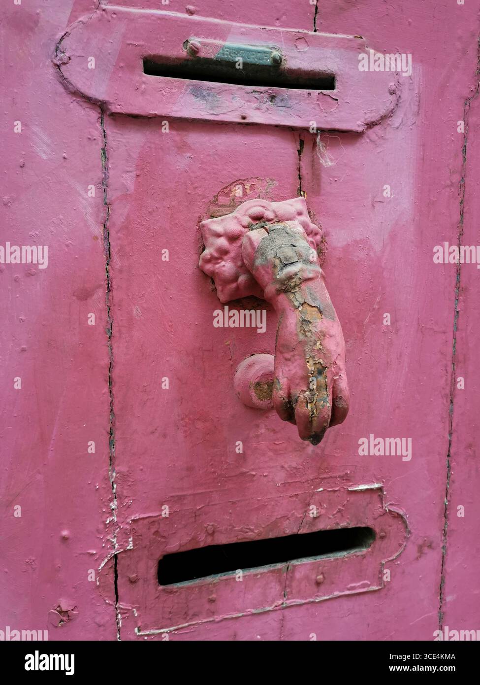 La parete intemprata presenta una caratteristica fessura rosa per posta con un manico vintage per leoni. Francia Foto Stock