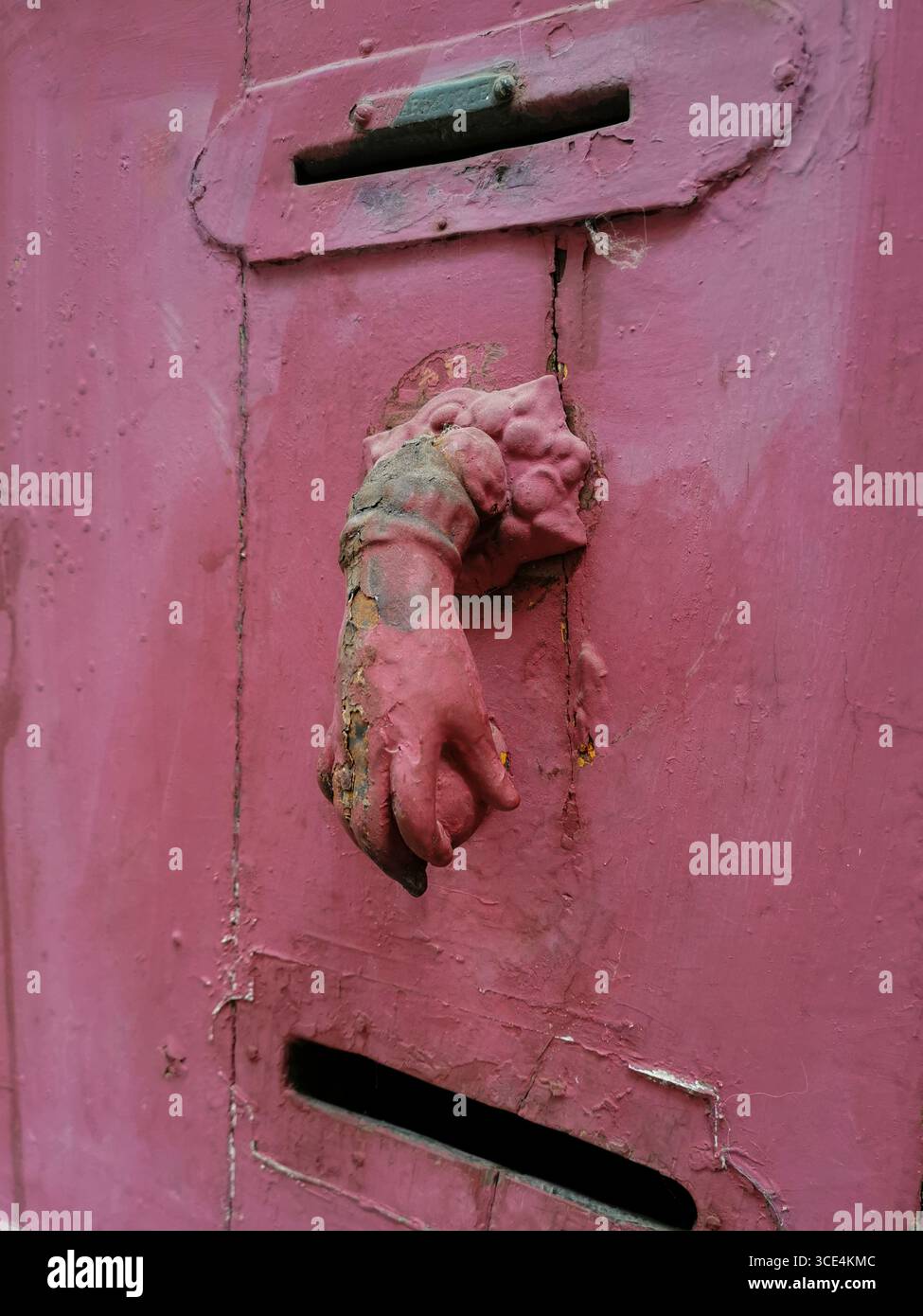 La parete intemprata presenta una caratteristica fessura rosa per posta con un manico vintage per leoni. Francia Foto Stock